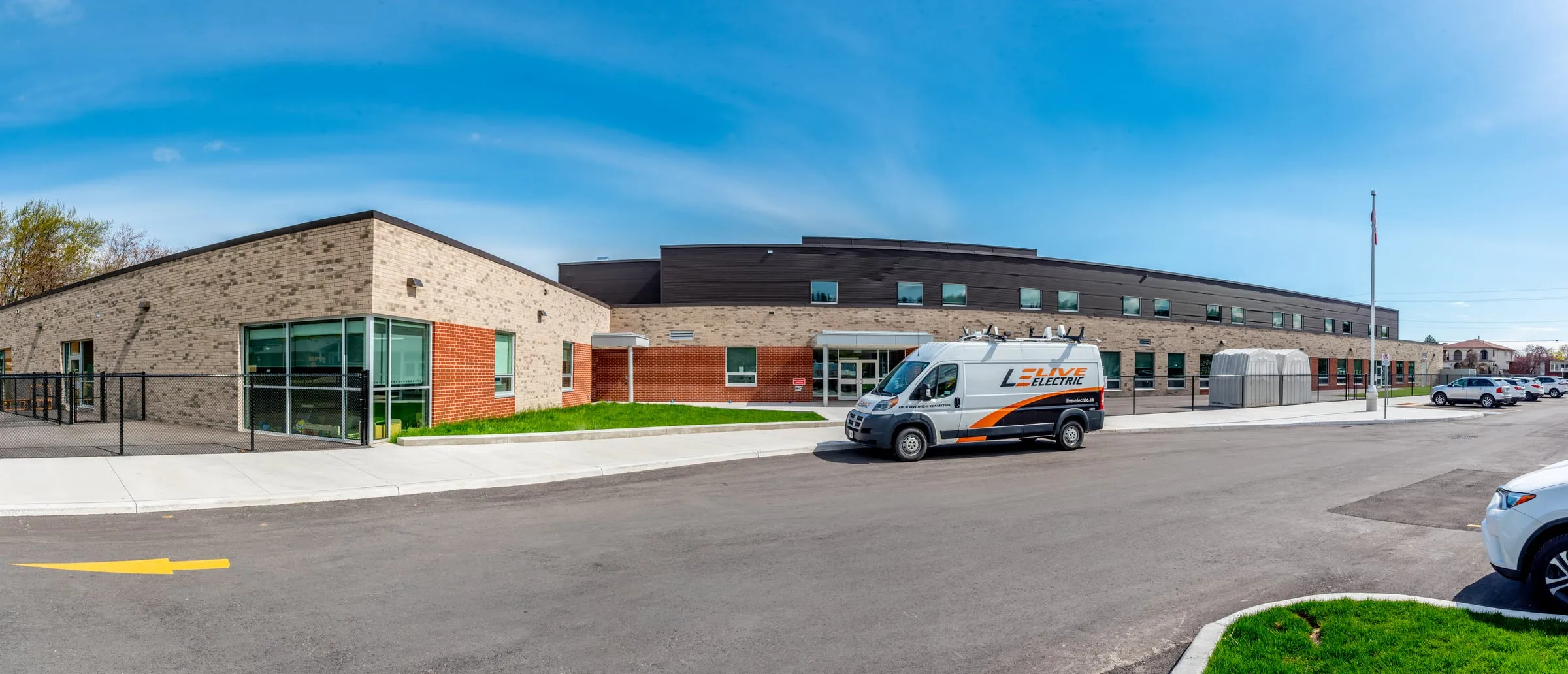 Panorama of a newly built elementary school with a Live Electric van parked at the entrance