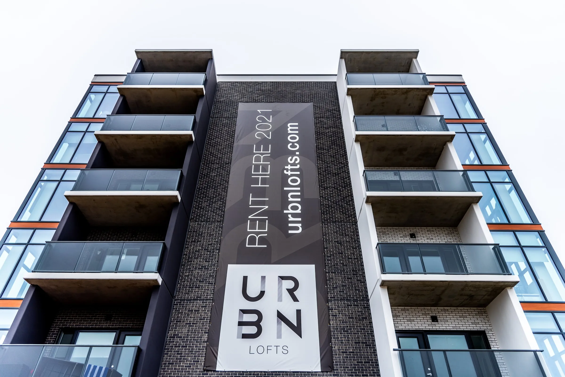 Exterior of the URBN Lofts mid-rise condominium in Guelph with balconies and a rental banner