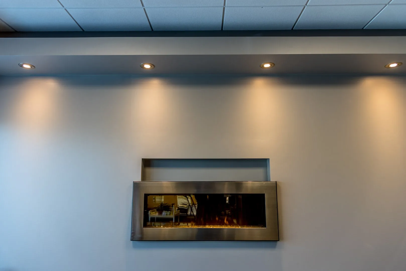 Renovated office lounge wall with a linear fireplace and recessed downlights