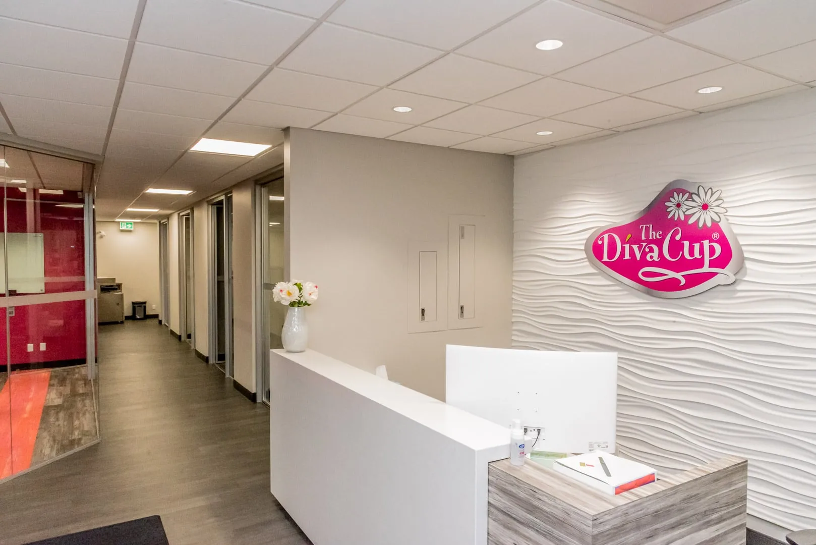 DivaCup head office reception with a backlit logo wall and glass-walled offices